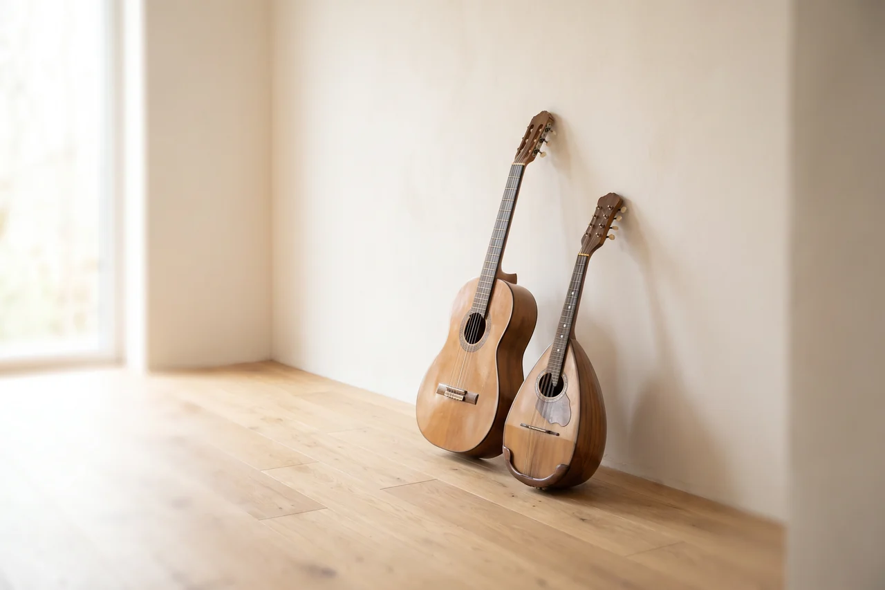 Una guitarra española y una mandolina italiana apoyadas una al lado de la otra contra una pared blanca